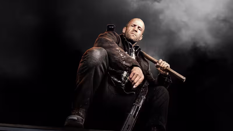 映画ワーキングマンのキービジュアル。ジェイソン・ステイサムがハンマーを構えて無骨な表情でしゃがんでいる。