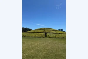 Landscape of grassy hills and straight paths under a blue sky