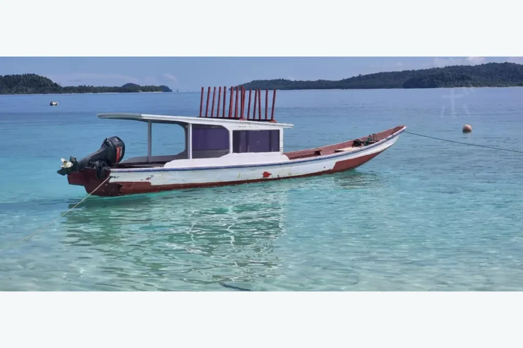 透明な浅瀬に静かに浮かぶ小さな木造船