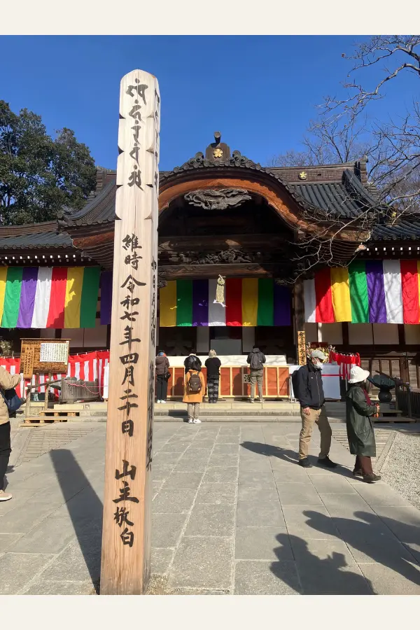 参拝者とともに写る、時の記録を刻んだ柱と深大寺本堂。