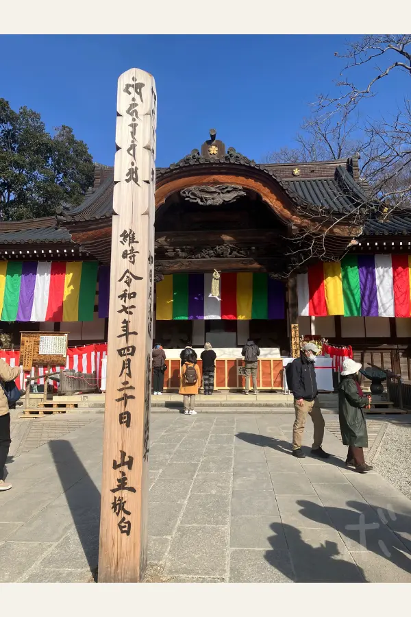 The main hall of Jindaiji Temple with a pillar inscribed with a record of time, shown with worshippers.