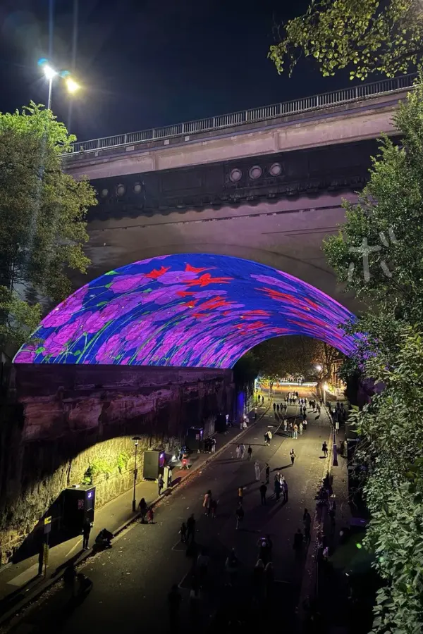 Tunnel wrapped in light and people walking under it