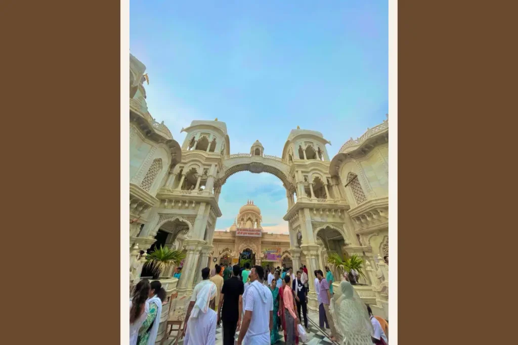 アーチ状の門が連なるインドの寺院で、祈りの場へ向かう人々が行き交う日常の風景