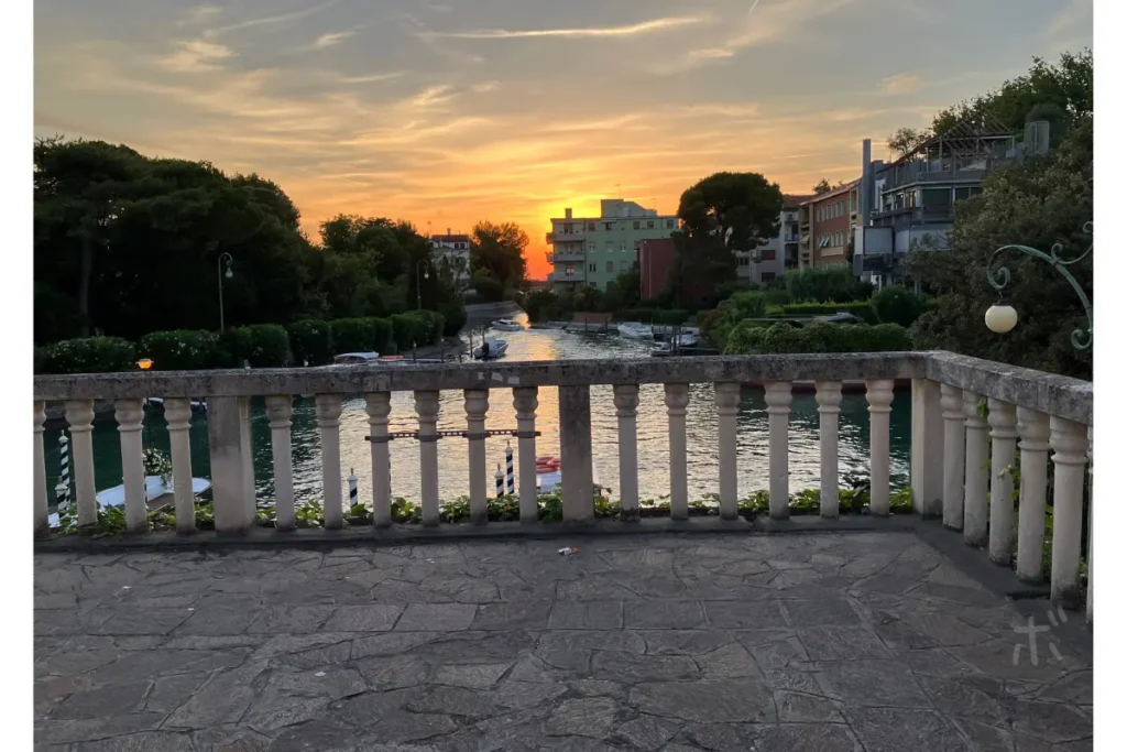 ヴェネツィア・リドの運河と石の欄干を前景に、夕暮れの空が広がる風景。