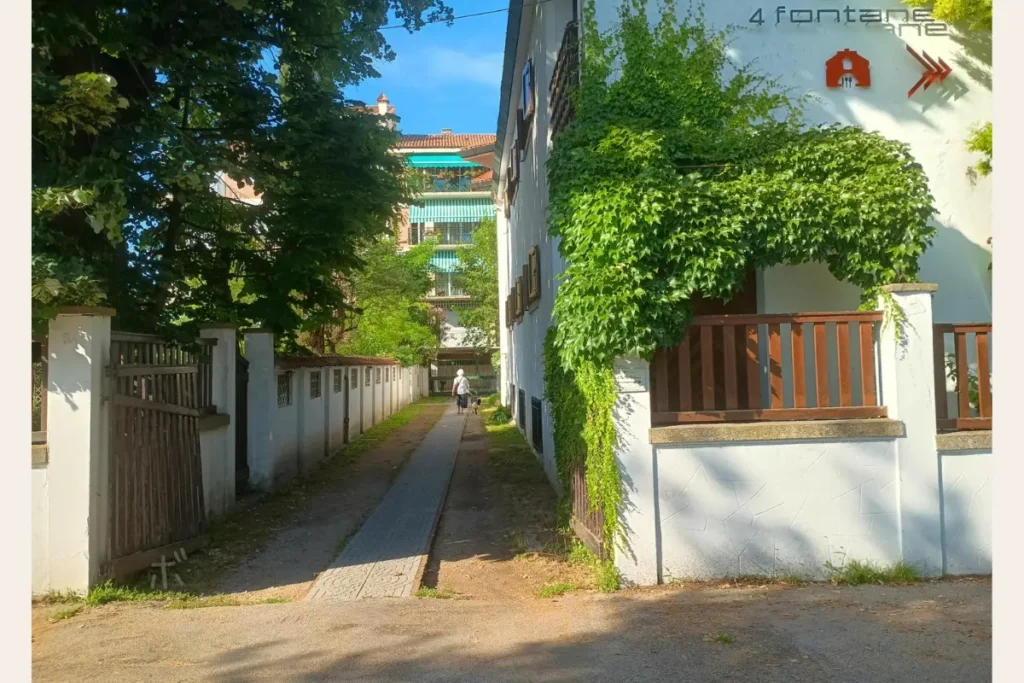 ヴェネツィア・リドの緑に包まれた小道を、お婆さんが犬と一緒に歩いている風景。