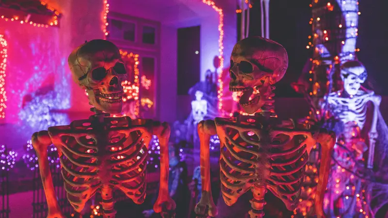 紫とピンクのネオンに照らされた2体のハロウィンの骸骨