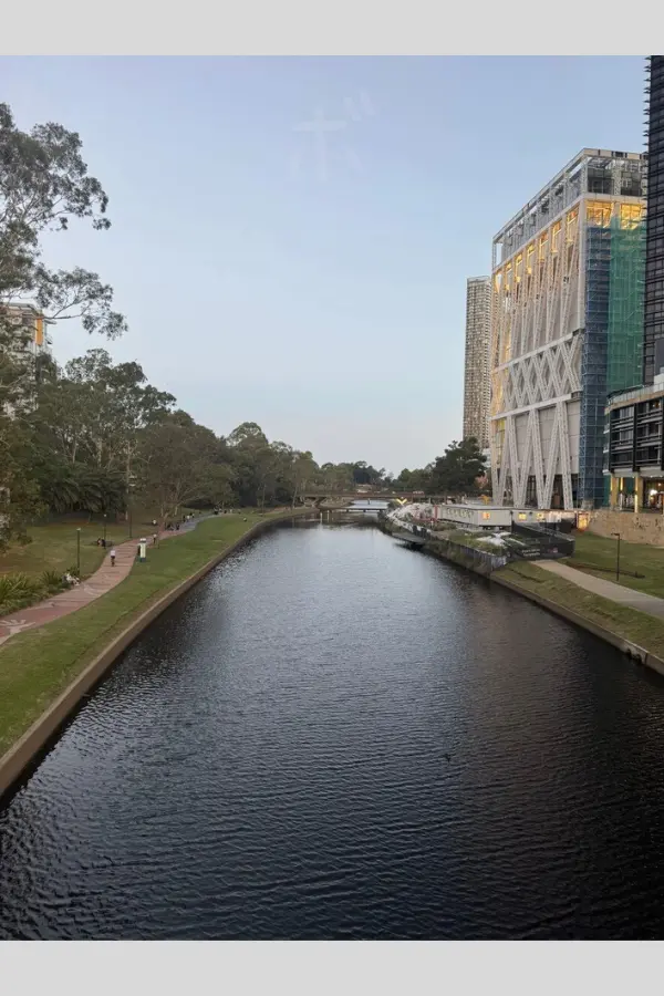 View looking down on the Parramatta River from above before dusk. The road and buildings along the river continue quietly.