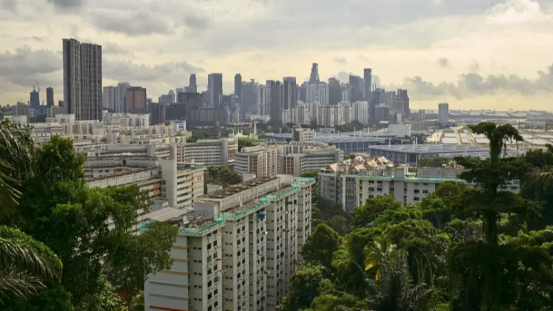 熱帯の濃い緑と住宅地の向こうに高層ビル群が広がるシンガポールの都市風景。