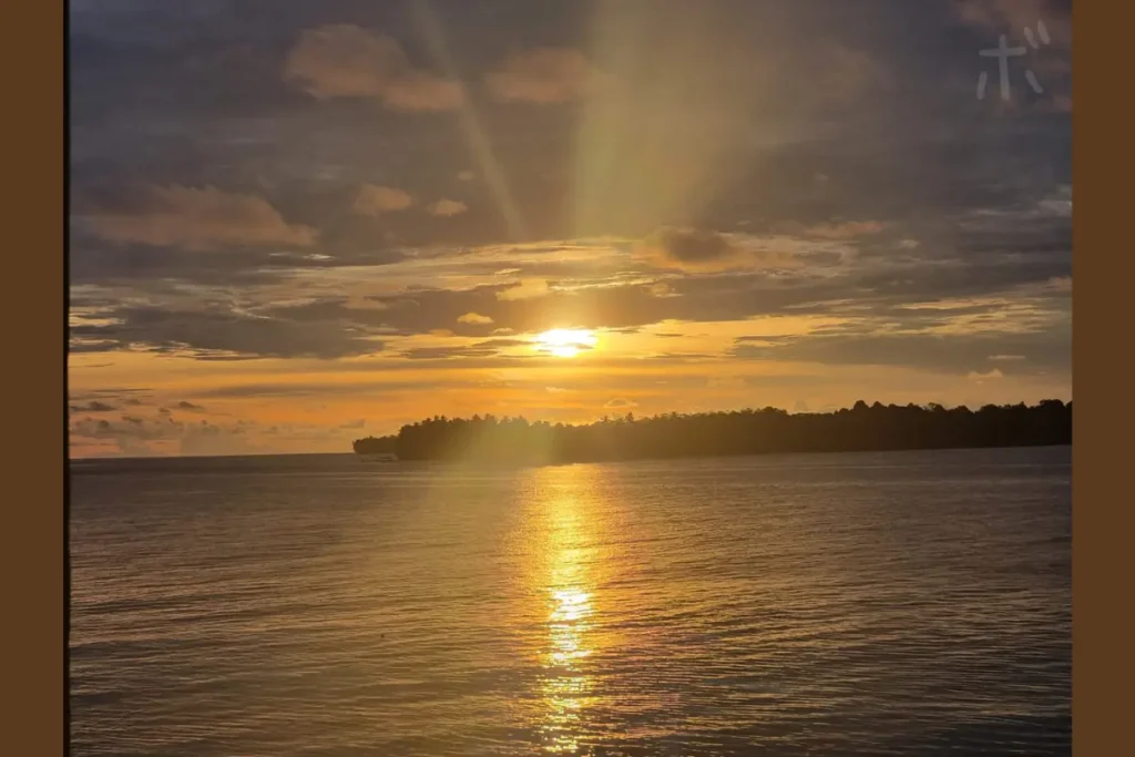 A view of the setting sun over the island with the light falling straight onto the surface of the sea.