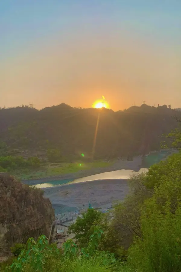 インドの川と山々の向こうに沈む夕日と、穏やかな夕暮れの景色