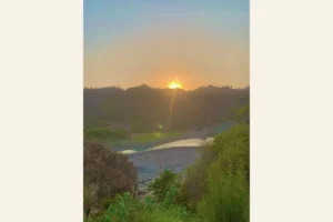 インドの川と山々の向こうに沈む夕日と、信仰と日常が静かに溶け合う風景