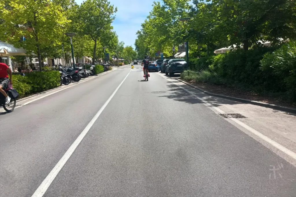 ヴェネツィア・リドの木陰が続く通りを、自転車が走っている昼の街並み。