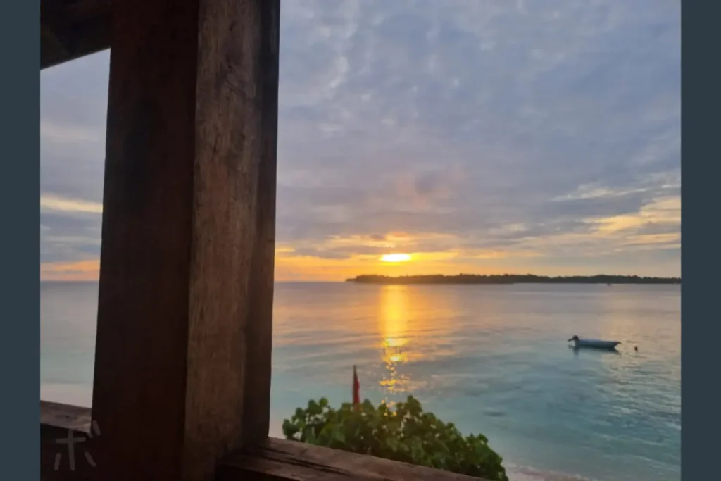 The view of the calm sea and sunset sky seen through the wooden window frames.