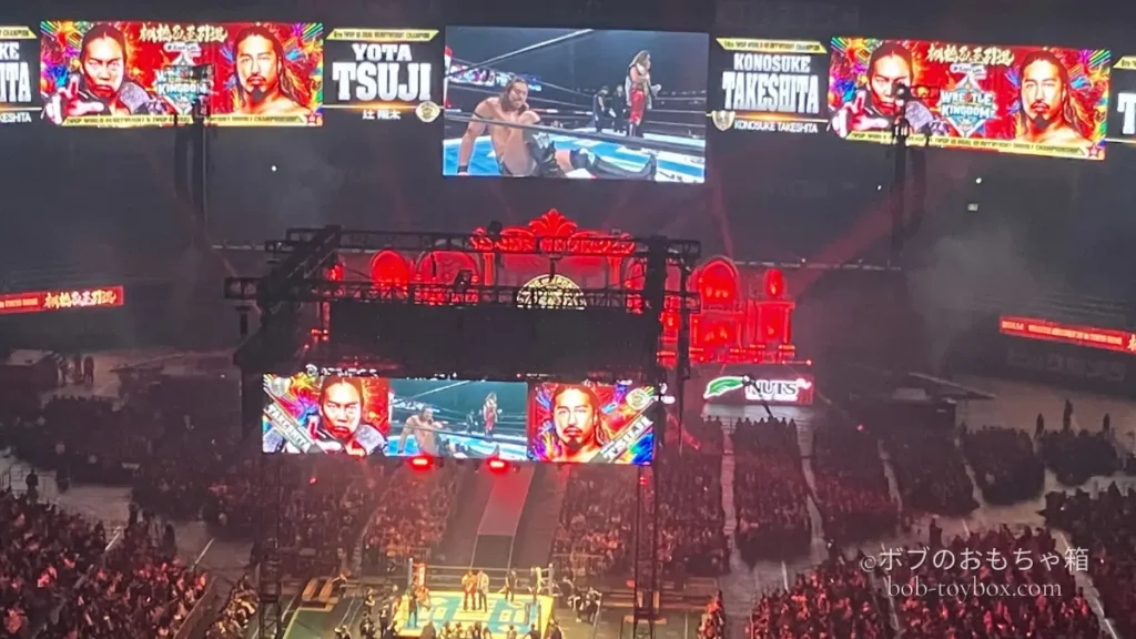 東京ドームの大型スクリーンに映し出された辻陽太と竹下幸之介の試合シーン。リング上と観客席を含めた会場全体の様子が写っている。