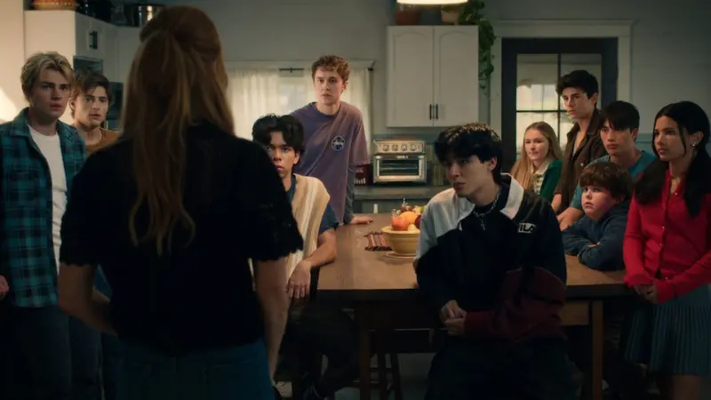 Still from Season 3 of the Netflix drama “My Life with the Walter Boys.” Family members and young people are gathered in the kitchen, looking toward a woman standing in front of them.