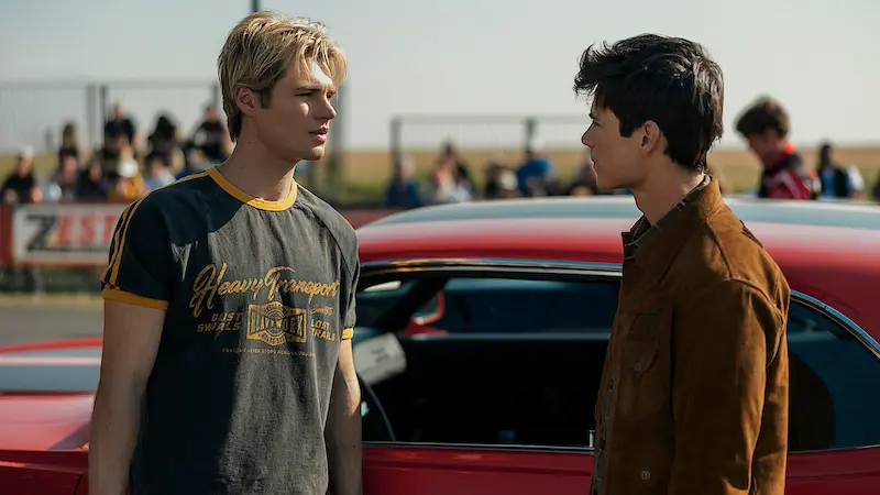Still from Season 3 of the Netflix series “My Life with the Walter Boys.” Two young men are facing each other in front of a red car.